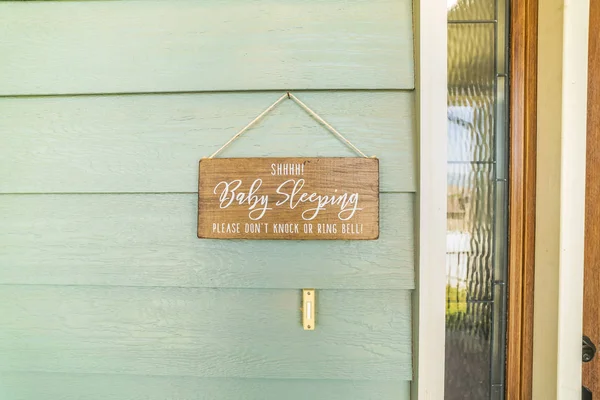 Cartel de bebé durmiendo colgado en la pared verde y por encima del timbre de una casa —  Fotos de Stock