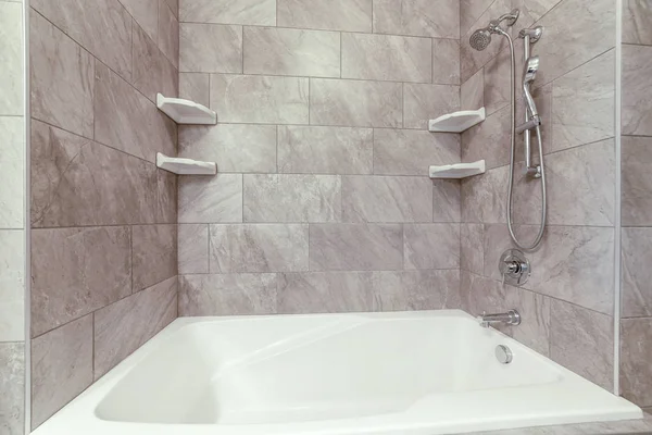 Square bathtub and stainless steel shower against gray and white tile wall — Stockfoto