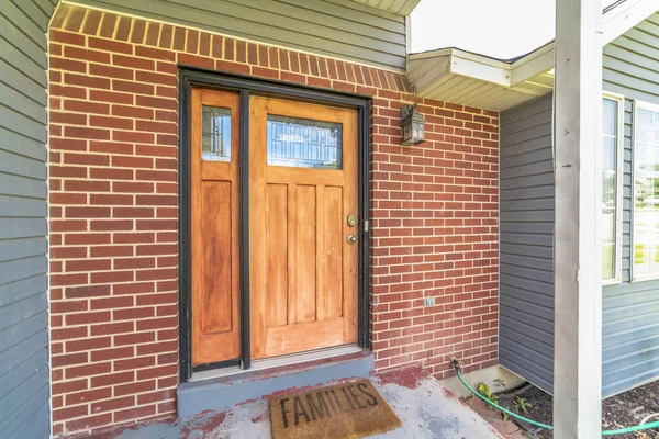Otthon téglával és fából készült fali részekkel és üvegtáblás bejárati ajtóval és oldalfénnyel — Stock Fotó