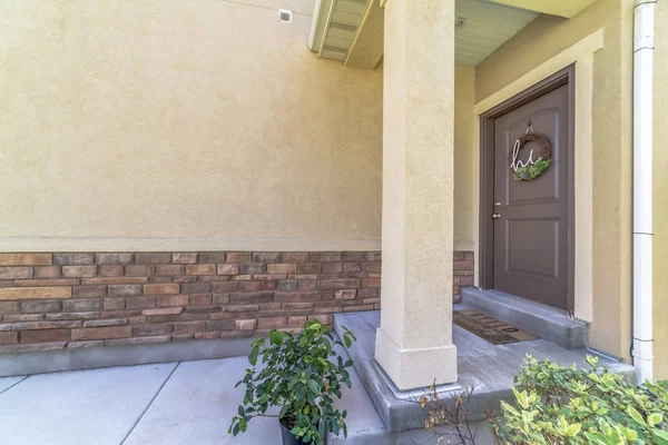 Entrada a casa con puerta pequeña porche y puerta frontal de madera marrón con corona — Foto de Stock