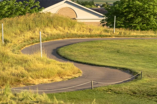 Close up of a narrow road curving in the middle of a grass covered terrain — Stock Photo, Image