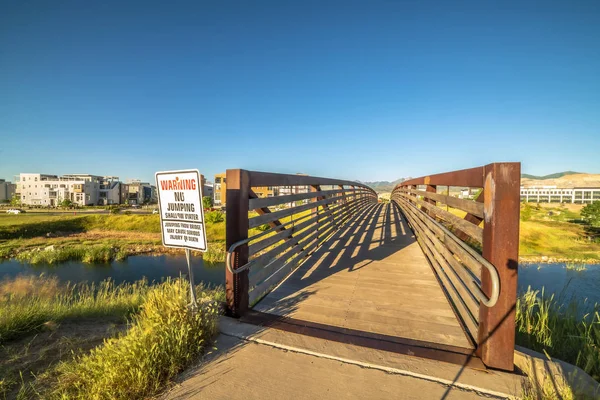 stock image Bridge over a lake with view of buildings mountain and blue sky on a sunny day