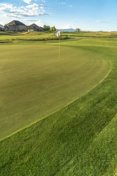 Vivid fairway verde de um campo de golfe com um buraco e bandeira no centro — Fotografia de Stock