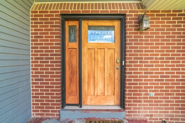 Glass paned brown door and sidelight against the red brick wall of a home — Stock Photo, Image
