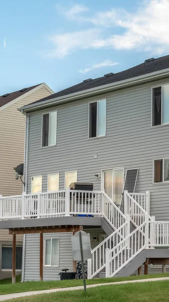 Gri yatay ahşap kaplamalı bir ev ve balkona çıkan merdivenler.