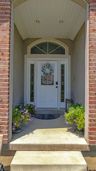 Vertical frame Flowers and white door with sidelights and transom window at the entrance a home