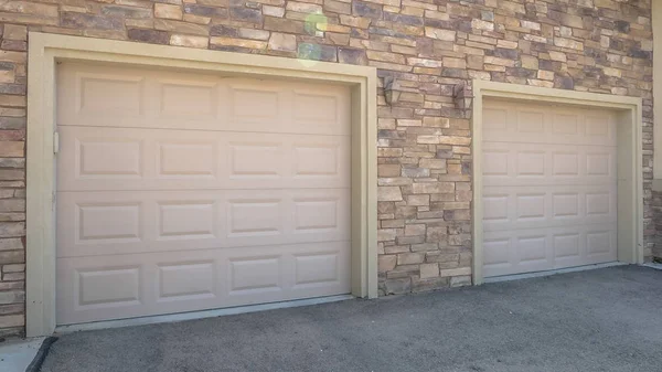 Marco panorámico Puertas de garaje blancas de una casa contra la pared exterior cubierta con ladrillos de piedra — Foto de Stock