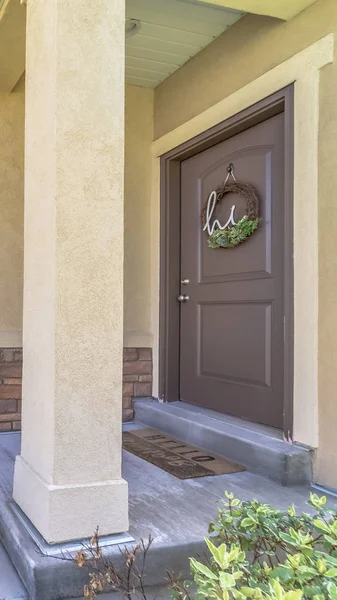 Vertical Home entrance with doorstep small porch and brown wooden front door with wreath
