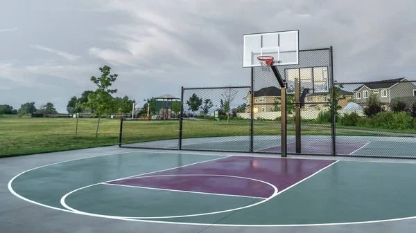 Panorama Canchas de baloncesto en un parque cerca de casas familiares de varios pisos bajo el cielo nublado — Foto de Stock