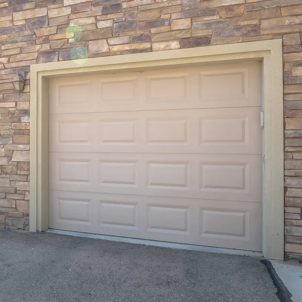 Квадратные белые двери гаража дома на фоне стены, покрытой каменными брикетами — стоковое фото