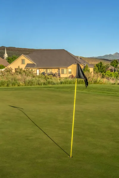 Yellow stick with a black flag at the tip against the fairway of a golf course Stock Image