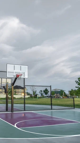 Vertical frame Basketball courts at a park near multi storey family homes under cloudy sky Stock Photo