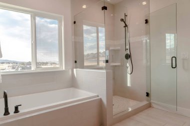 Built in bathtub with black faucet and shower stall with half glass enclosure clipart