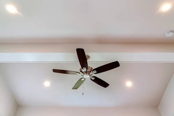 Ceiling fan with wood blades and built in lights on the ceiling beam of home