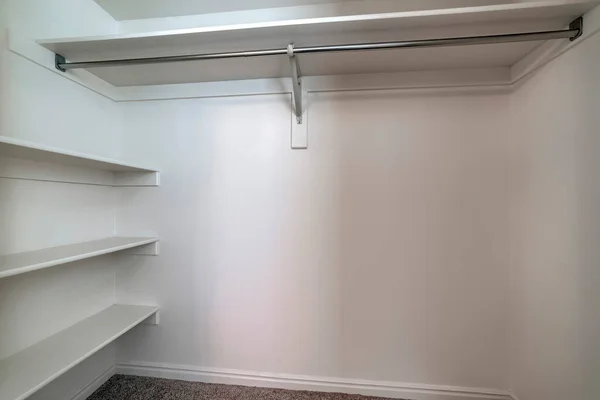 Empty walk in closet of new home with wall shelves and hanging clothes rod — Stock Photo, Image