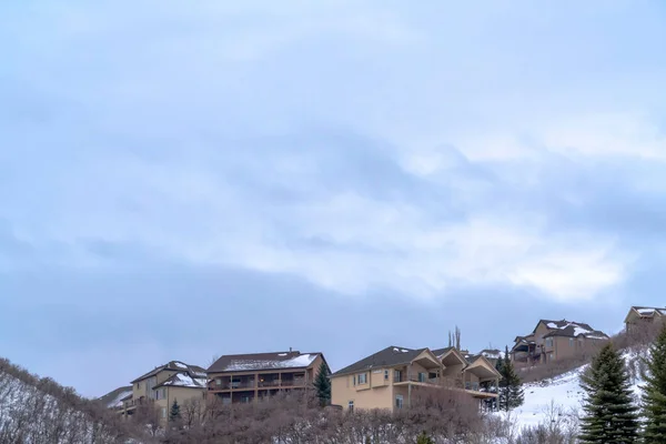 Nublado cielo azul sobre las casas en la cima de una colina cubierta de nieve blanca fresca en invierno — Foto de Stock