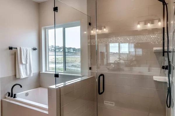 Frameless walk in shower stall and built in bathtub inside tile wall bathroom