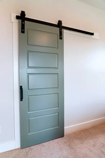 Closed sliding gray panel door with black handle against white wall of home
