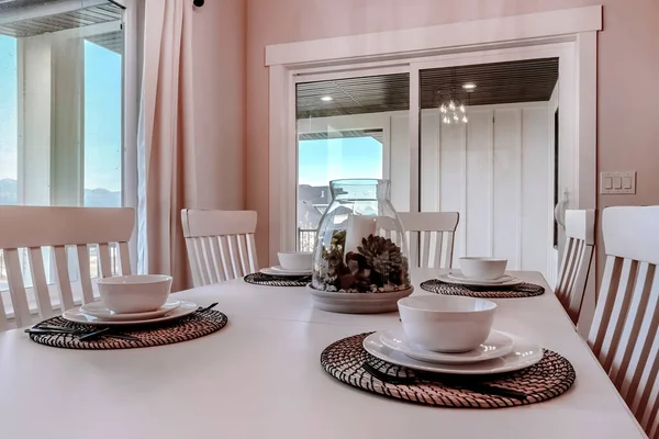 Dining table with chairs and tableware arranged around a decorative centerpiece