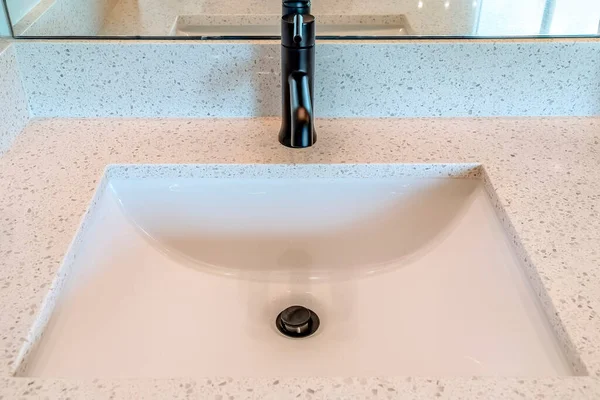 Primo piano del lavabo singolo con rubinetto nero sul piano di lavoro bianco — Foto Stock