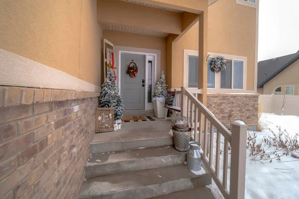 Wet stairs at home entrance leading to front door with christmas tree and wreath