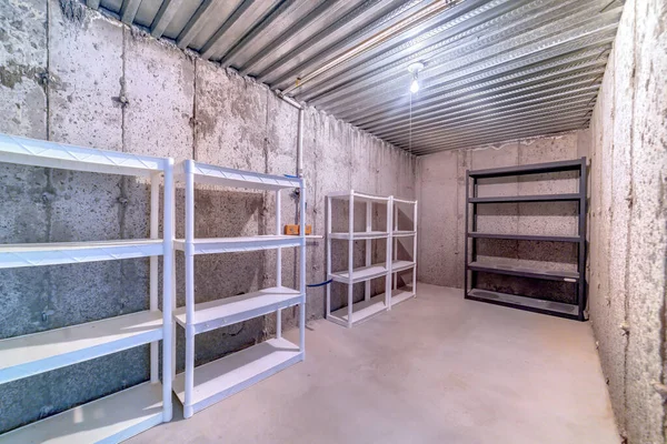 Supports métalliques multicouches vides à l'intérieur d'une salle de stockage avec mur et plancher en béton — Photo