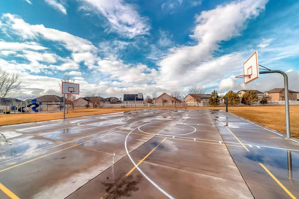 Basketball courts on grassy park with residential neighborhood houses background — Stock Photo, Image