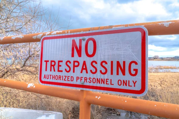 No Trespassing sign on an old metal fence against distant lake and cloudy sky — Stock Photo, Image