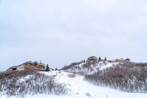 Casas en lo alto de una colina cubierta de nieve blanca fresca en un frío día de invierno — Foto de Stock