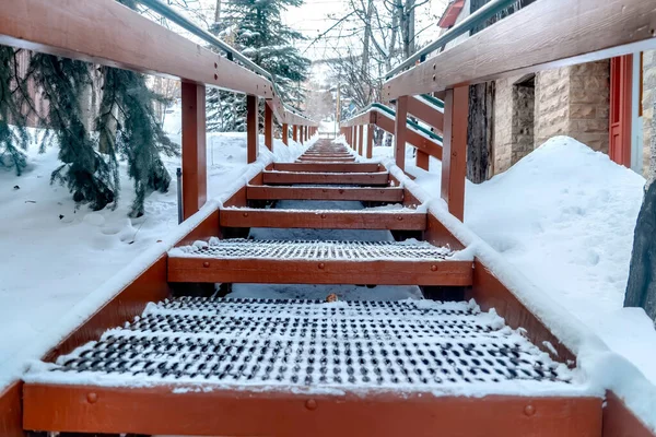 Enfócate en las bandas de rodadura metálicas de las escaleras exteriores contra la colina nevada en invierno — Foto de Stock