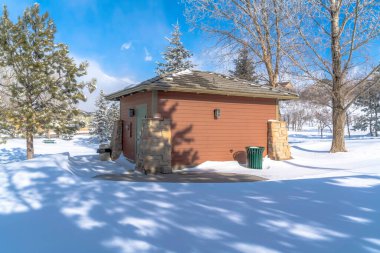 Kalça çatılı depo ve kar ve bulutlu gökyüzüne karşı kahverengi ahşap duvar