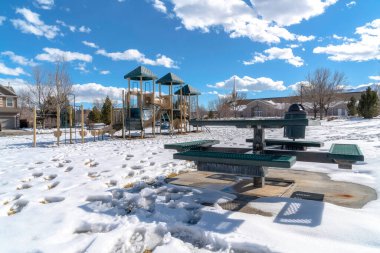 Oyun alanı ve piknik masası kışın karla kaplı zeminde ayak izleri.