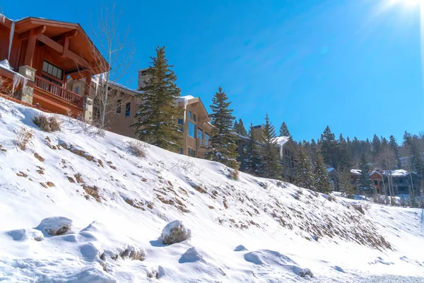 Fachada de belas casas em uma encosta coberta de neve branca em um dia ensolarado de inverno — Fotografia de Stock