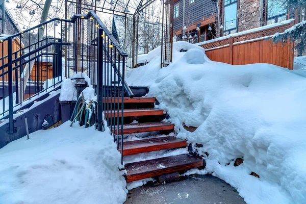 Outdoor stairway with string lights on handrails against snowy slope in winter