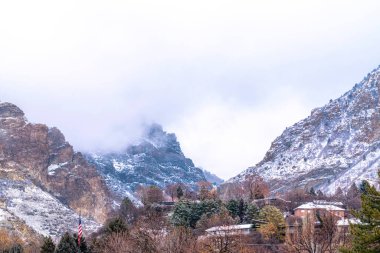 Utah 'taki engebeli Provo Kanyonu bulutlu bir kış gününde karlı evlerin üzerinde yükseliyor.