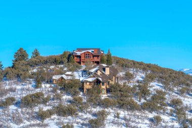 Park City Utah 'taki tepedeki evler kışın kar ve mavi gökyüzünün ortası