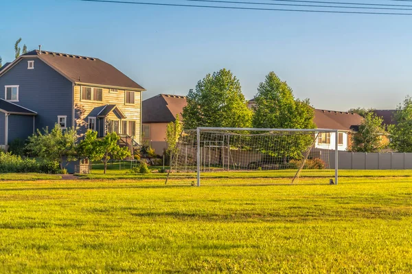 Fútbol gol en el vasto campo de hierba verde en frente de las casas vistas en un día soleado —  Fotos de Stock