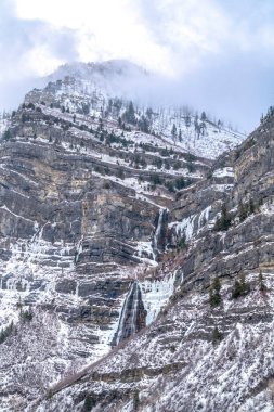 Utah 'taki Provo Kanyonu' nda kışın bulutlu gökyüzünün altında kar yağışı var.