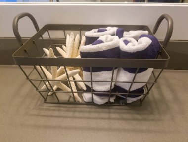Evin banyosunda yüz havlusu ve süngerli metal depolama sepeti.
