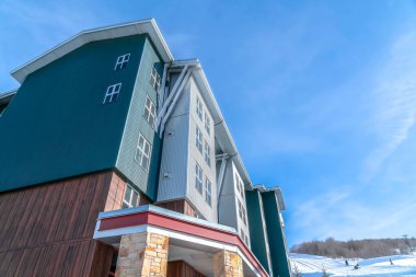 Güneşli mavi gökyüzüne ve kışın karla kaplı tepelere karşı lüks bir ev.