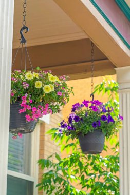 Güzel bir evin verandasında zincirlenmiş renkli saksılar.