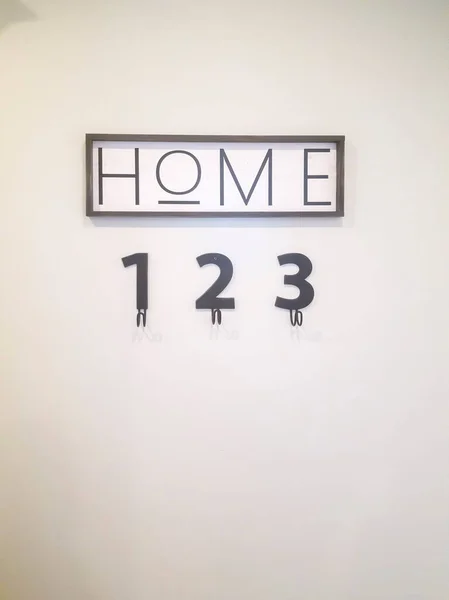 Close up of wall decoration that reads Home over number decors with hooks — Stock Photo, Image