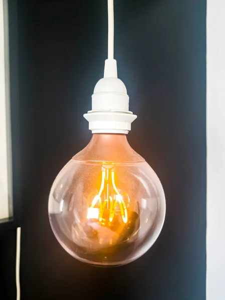 Lampadina elettrica con tappo bianco e filo isolato su sfondo nero — Foto Stock