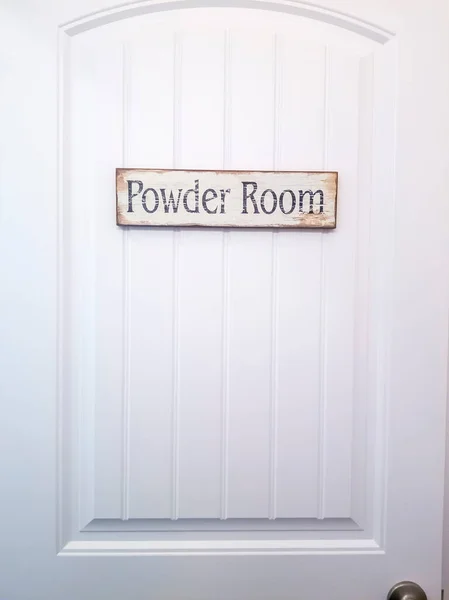 White panelled door with rustic rectangular wooden Powder Room sign