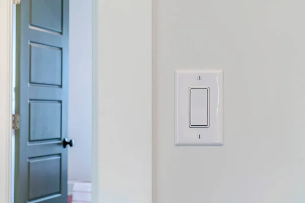 Elektrisk rocker ljus switch på vit vägg mot suddig dörr bakgrund — Stockfoto