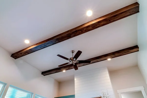 Ceiling fan with lights flanked by decorative wood beams and recessed lighting — Stock Photo, Image