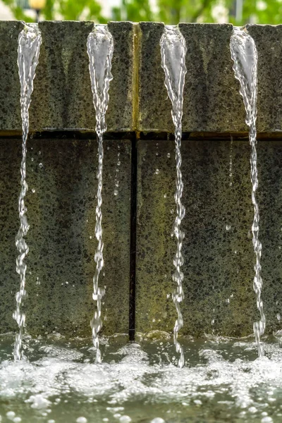 Close up de água brilhante de uma fonte escorrendo para baixo em uma piscina clara — Fotografia de Stock