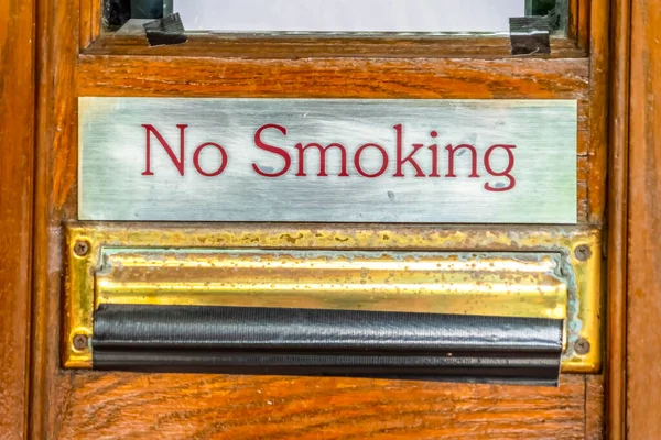 No Smoking segno sopra slot goccia posta con nastro nero contro porta di legno marrone — Foto Stock