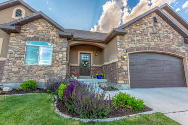 Taştan duvarın ve gable çatılarının önündeki yemyeşil bahçeli evin ön cephesi