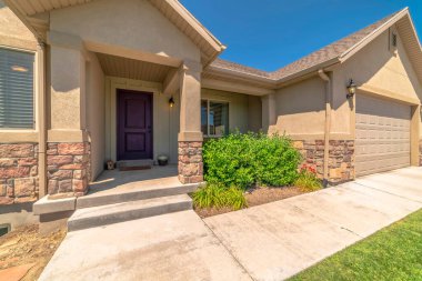 Evin ön cephesinde mavi gökyüzüne karşı girişi ve garajı olan gable çatıları var.